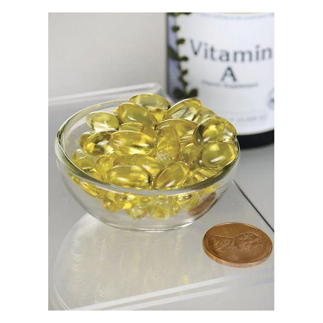 A small glass bowl of yellow vitamin capsules sits beside a coin, promoting strong eyesight. A partially visible Swanson Vitamin A 10000 IU 250 Softgels bottle in the background hints at supporting a healthy immune system.