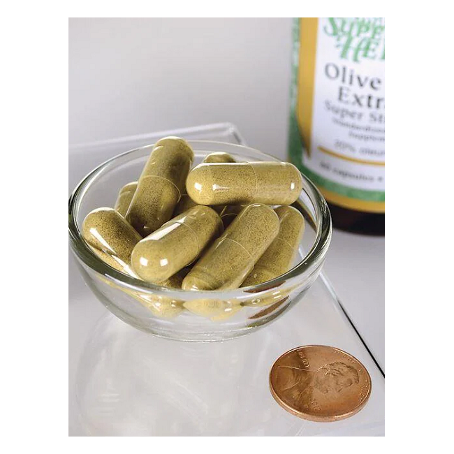 A small glass bowl contains several olive green capsules beside a penny for scale. In the background, a partially visible bottle labeled "Swanson Olive Leaf Extract 750 mg 60 Capsules" suggests powerful immune support thanks to its oleuropein content.