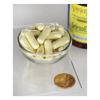 Thumbnail for A small glass bowl holding yellow selenium capsules lies on a transparent surface next to a penny for size reference. In the background is a partially visible bottle labeled 