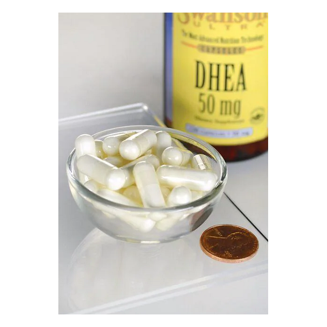 A small bowl with white capsules is next to a Swanson DHEA - 50 mg bottle and a penny for scale, highlighting its role in supporting hormonal balance and promoting bone health.