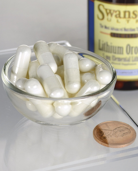 A bowl of white capsules is placed next to a penny, with a bottle labeled "Swanson Lithium Orotate 5 mg 60 Veggie Capsules" in the background, emphasizing its potential role in mood stabilization for emotional health.