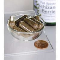 Miniatura de Swanson's Schizandra Berries - 525 mg 90 capsules, um tónico hepático e adaptogénico, estão expostas numa tigela ao lado de uma moeda.
