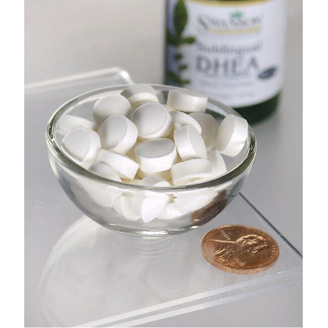 Uma taça de comprimidos brancos ao lado de um frasco de Swanson DHEA - 25 mg 60 pastilhas com sabor a cereja.