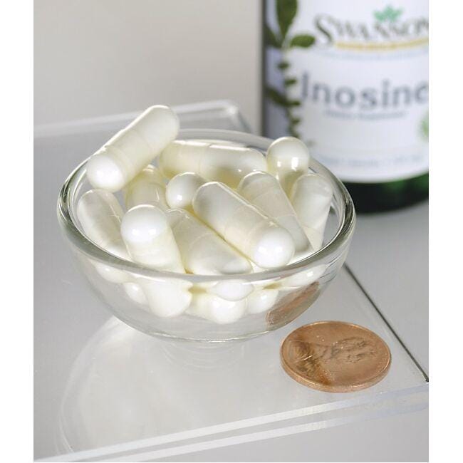 Uma tigela de comprimidos brancos ao lado de um frasco de Swanson Inosine - 500 mg 60 vege capsules.