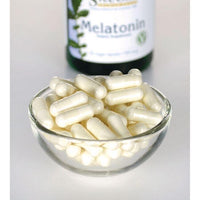 Miniatura de Swanson Melatonin - 0,5 mg 60 cápsulas vegetais numa taça de vidro ao lado de um frasco.