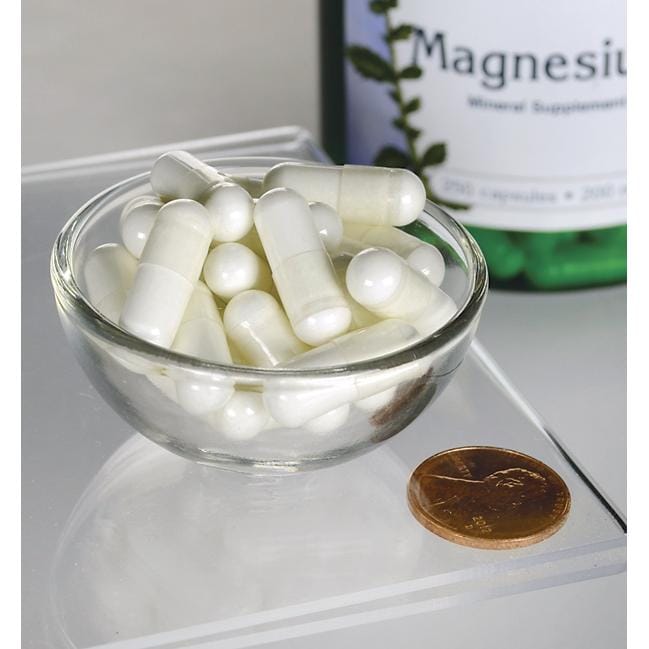 Uma tigela de comprimidos brancos ao lado de um frasco de Swanson Magnesium Oxide - 200 mg 250 capsules.