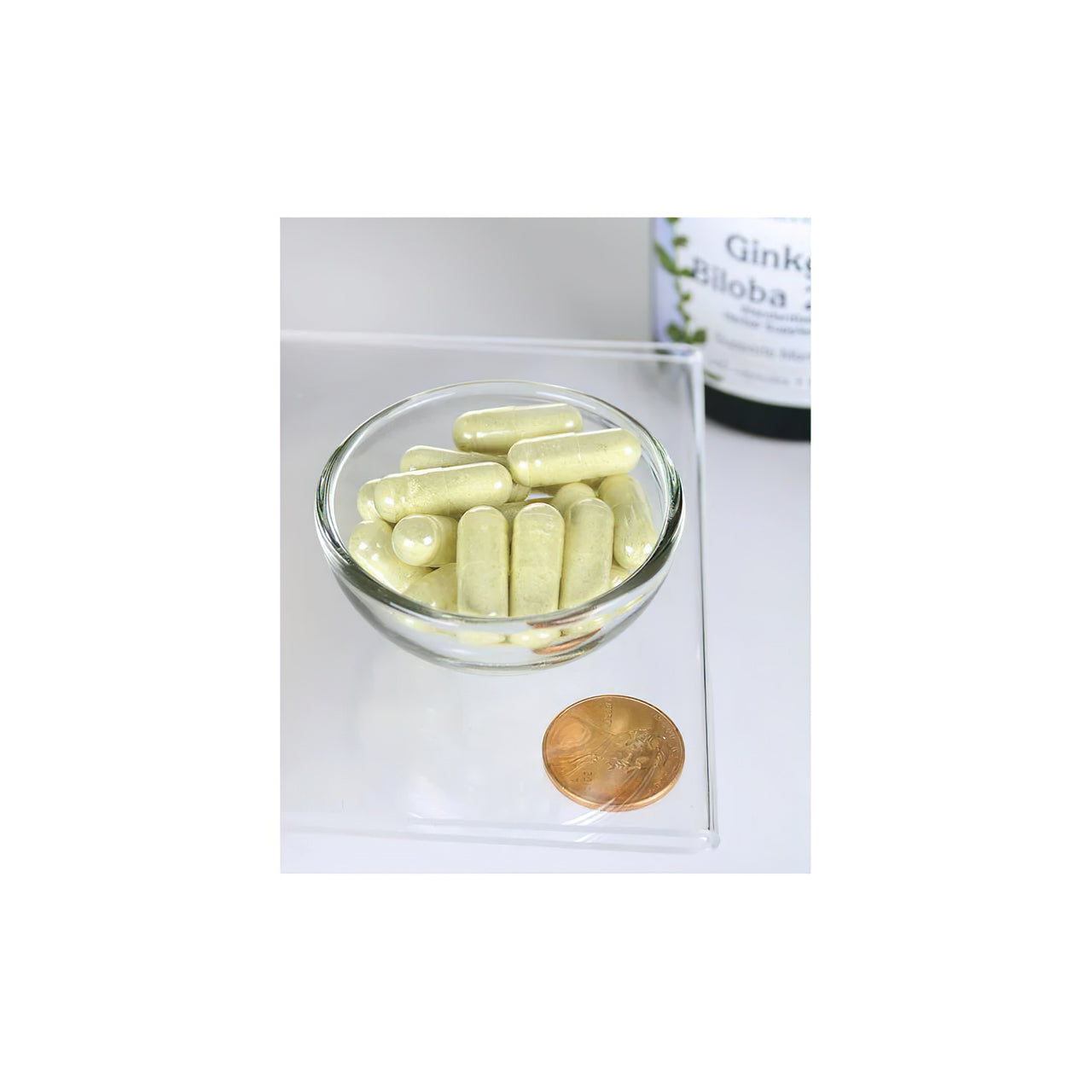 Uma taça de Swanson Ginkgo Biloba Extract 24% 60 mg 240 cap com uma moeda ao lado.