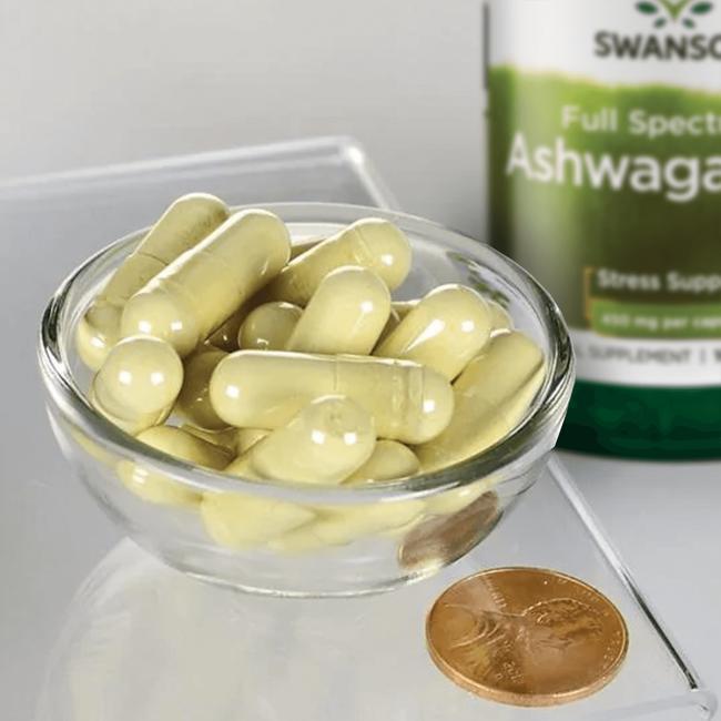 Uma taça de Swanson Ashwagandha - 450 mg 100 capsules com uma moeda ao lado.
