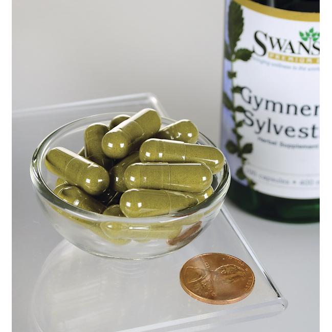 Um frasco de Swanson Gymnema Sylvestre Leaf - 400 mg 100 cápsulas com uma moeda numa tigela.