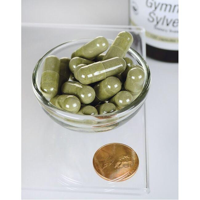 Uma taça de Swanson Gymnema Sylvestre Extract - 300 mg 120 capsules ao lado de uma moeda.