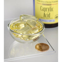 Miniatura de Swanson's Caprylic Acid - 600 mg 60 softgel dietary supplement capsules numa taça ao lado de uma moeda.