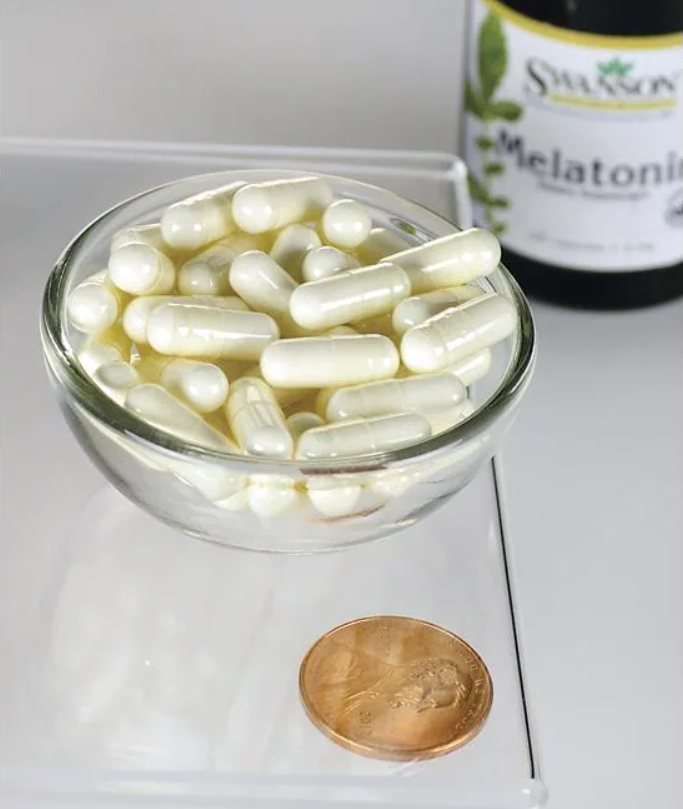 Uma taça de Swanson Melatonin - 3 mg 120 capsules ao lado de um cêntimo.
