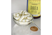 Miniatura de Swanson DHEA - 100 mg 60 cápsulas numa taça ao lado de uma moeda.